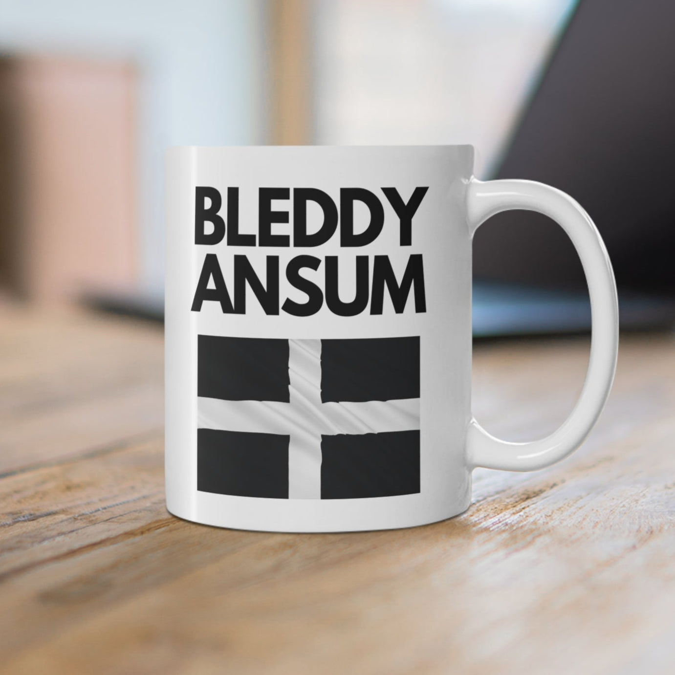 White ceramic mug with bold text “Bleddy Ansum” and the black and white Cornish flag (St Piran’s Flag) – a funny Cornwall-themed coffee mug.