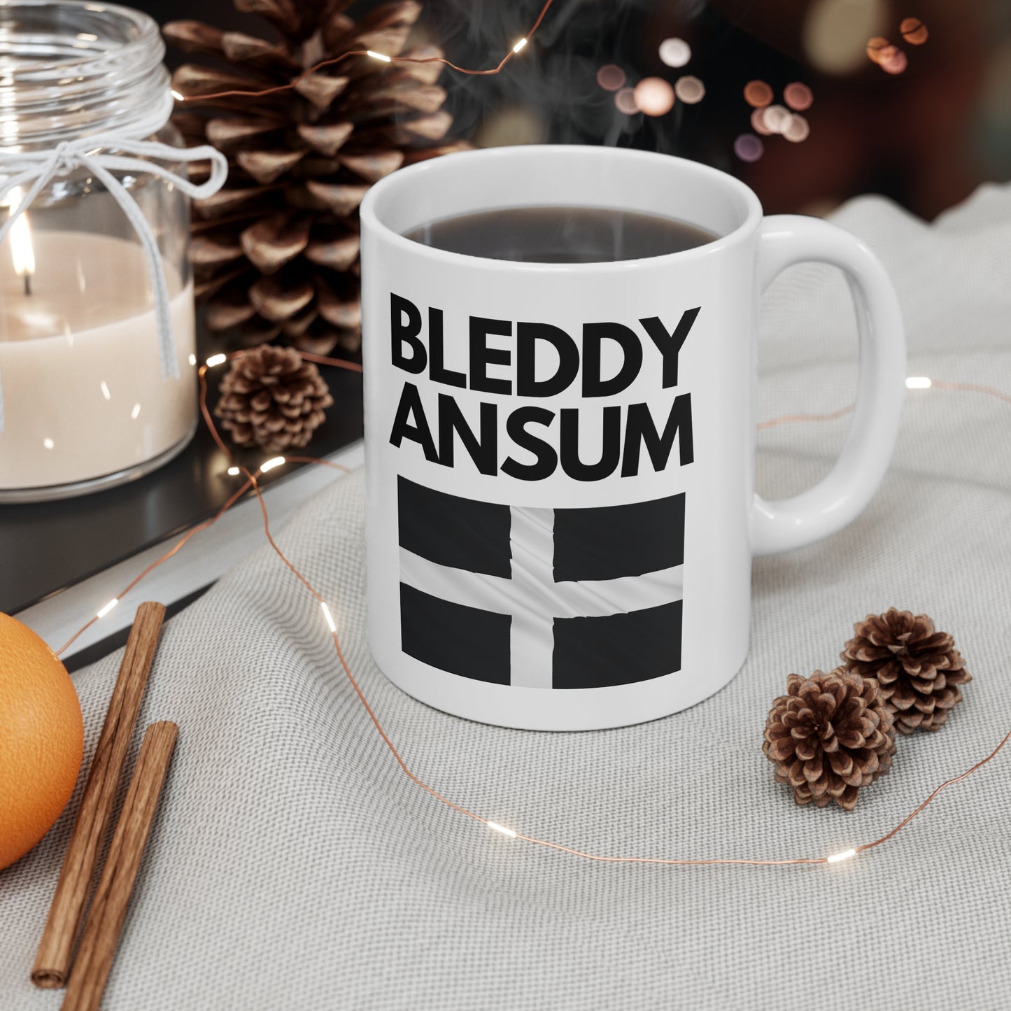 White ceramic mug with bold text “Bleddy Ansum” and the black and white Cornish flag (St Piran’s Flag) – a funny Cornwall-themed coffee mug.