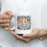 Person holding a mug with 'Beautifully Dead Inside' text design.