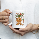 Person holding a mug with a gingerbread man design and 'Oh Snap!' text.